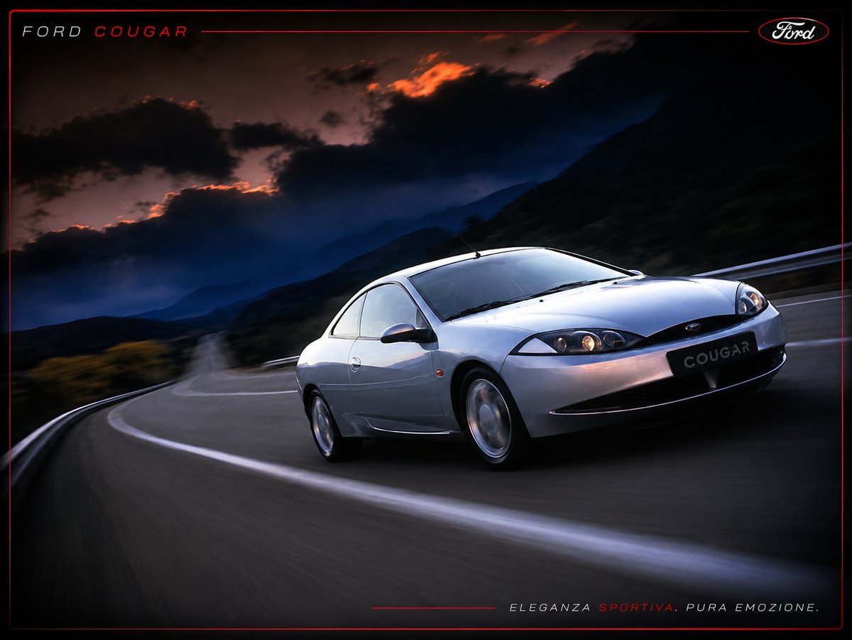 Ford Cougar argento su strada di montagna al tramonto